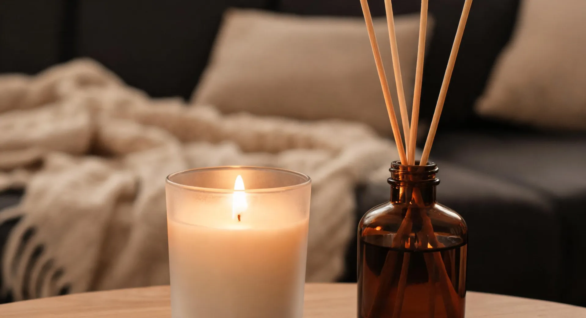 Lit Homesick candle and reed diffuser in a cozy living room corner